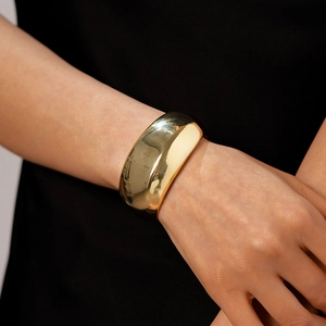 Macro detail of high-polish gold wide cuff bracelet showing mirror-like metallic finish