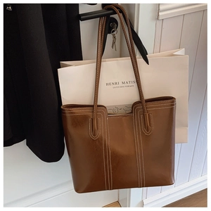 Detailed shot of brown vintage tote bag featuring white contrast stitching and oil wax texture