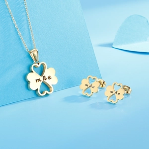 Detail of gold clover necklace and earrings set with mãe engraving on blue heart card