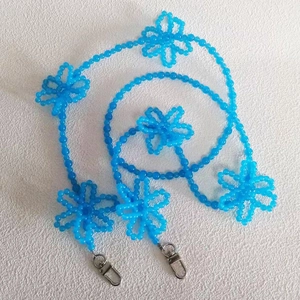 Close-up of blue beaded crossbody strap with handmade acrylic flower accents and metal clasps