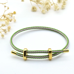 Detail of adjustable green and purple woven cord bracelet with gold metal clasp accents