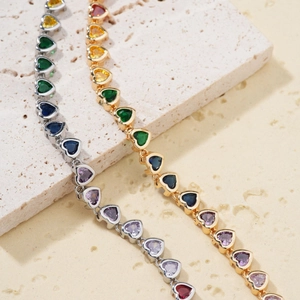 Macro shot of gold and silver heart-shaped tennis bracelets with colorful zircon stones