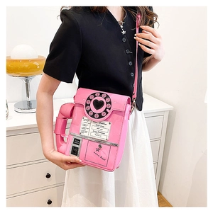 Detail of pink retro telephone shaped crossbody bag featuring a heart dial on a model