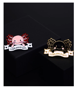 Detailed view of axolotl enamel pins featuring I like you a lotl quote on black display