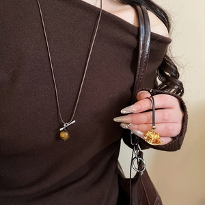 Close-up of tiger eye stone pendant and golden rocking horse necklace on model