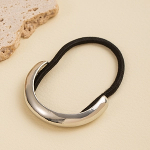 Detail of a black elastic hair tie with a minimalist silver C-shaped metal ornament