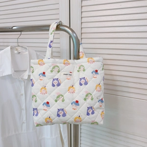 Close-up of a white quilted tote bag featuring colorful cartoon girl prints and logo