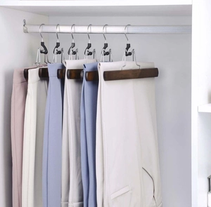 Solid wood pants hangers with velvet non-slip clips holding multiple colored trousers