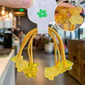 Detailed macro view of four yellow gummy bear hair ties with handmade card packaging