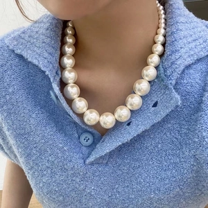 Collier de perles dégradées rétro français avec grandes perles blanches sur pull bleu