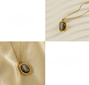 Detail of 18K gold titanium steel necklace featuring an oval grey natural stone pendant