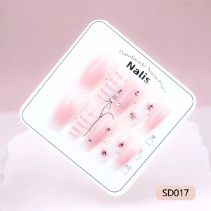 Detail of pink gradient press-on nails with star sequins and rhinestones on display card