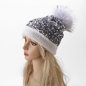 Detail of silver sequins and fluffy faux fur pompom on the winter knit beanie
