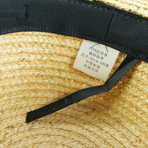 Close-up of the internal black sweatband and 100% raffia material label of the straw hat
