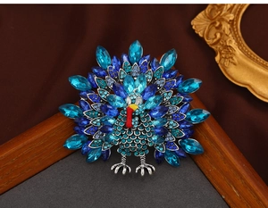 Macro shot of vintage turkey brooch with blue rhinestones and red enamel detail on satin