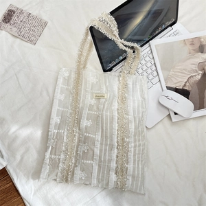 Vue détaillée du sac cabas en dentelle blanche avec broderie florale et franges