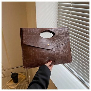 Detail showing brown crocodile-textured PU leather clutch with oval handle and flap buckle