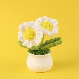 Macro shot of handcrafted crochet white daisies and green leaves in a white ceramic pot