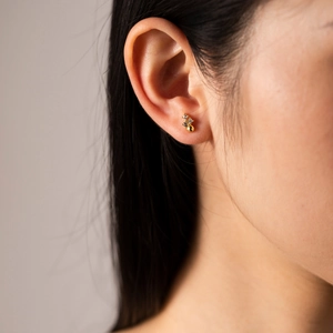 Macro shot of minimalist gold S925 silver stud earring with three small zircon stones