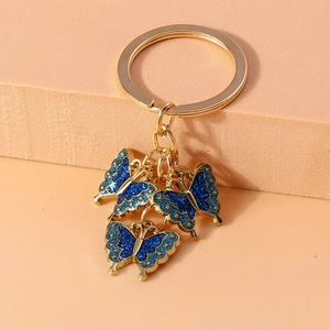 Golden butterfly keychain featuring three blue enamel pendants with glitter accents