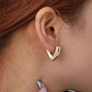 Close-up of heart-shaped gold huggie earrings with polished mirror finish on ear