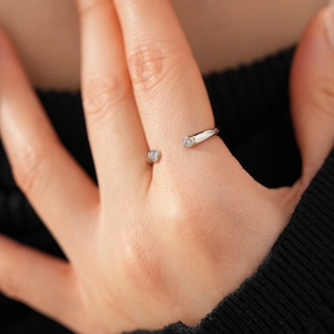 Détail macro d'une bague ajustable argentée ornée de deux zircons ronds étincelants