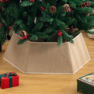 Jupe de sapin de Noël hexagonale en lin beige avec boîtes cadeaux sur parquet en bois
