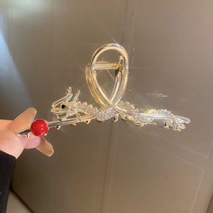Detail of golden dragon hair claw with sparkling rhinestones and red pearl accent