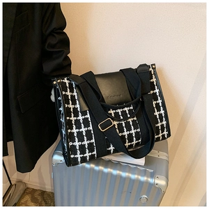 Detail van zwart-wit geblokte tweed shopper geplaatst op een zilveren koffer