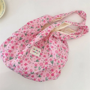 Close-up of pink floral tote bag with textured puff fabric and branded woven label