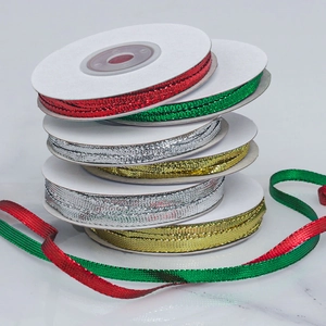 Macro shot of metallic red, green, gold, and silver ribbons on grey marble background