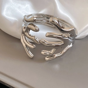 Macro shot of branch-shaped silver cuff bracelet with liquid metal finish on silk