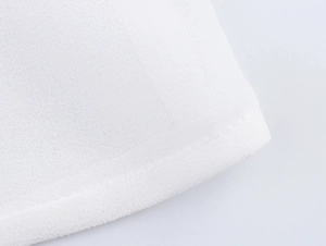 Macro shot of white chiffon fabric texture and edge stitching on elegant blouse