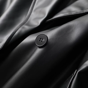 Macro detail of high-quality black leather grain and solid round buttons on the coat
