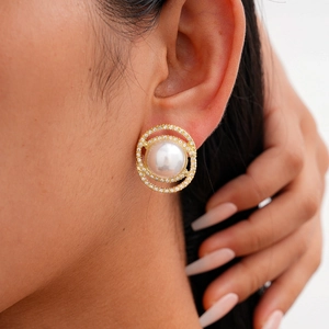 Elegant gold earrings set with large white pearls and tiny zircons shown on a model