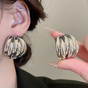 Macro detail of silver multi-layer spiral earrings featuring a polished mirror finish