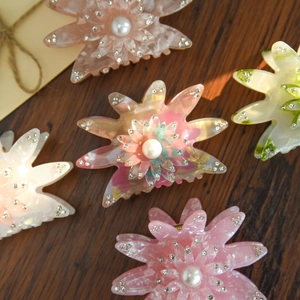 Détail de pinces à cheveux fleur avec perles et strass sur fond de bois foncé rustique