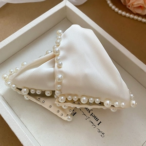 Détail d'une pince à cheveux élégante en satin crème avec perles et rivets argentés