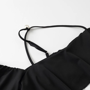 Dettaglio del top nero con spalline sottili e decorazione elegante con bottone di perla