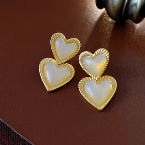 Macro shot of vintage gold heart earrings with white pearlescent inlay on leather