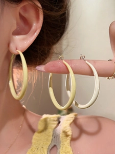 Detail of oversized yellow and cream enamel hoop earrings with a glossy polished finish