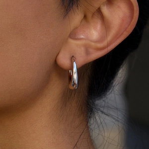 Close-up of triple-layered silver stainless steel C-shaped earring on model ear
