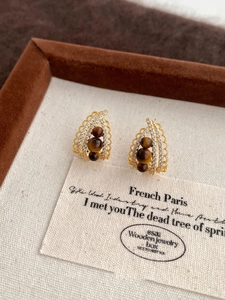 Macro detail of gold tiger eye earrings with sparkling cubic zirconia on brown velvet