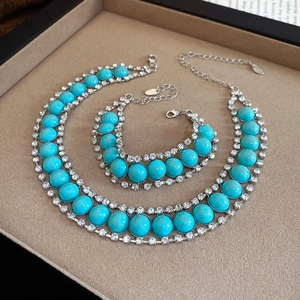 Détail d'un ensemble de bijoux bohème turquoise et strass dans un coffret en velours