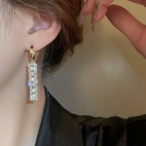 Close-up of golden geometric earrings with crystals on a model with sparkling star effect
