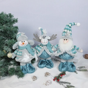 Detail of three plush Christmas dolls with knitted hats on a decorative snow background
