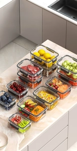 Detail of multi-size food storage containers with black airtight lids on marble surface