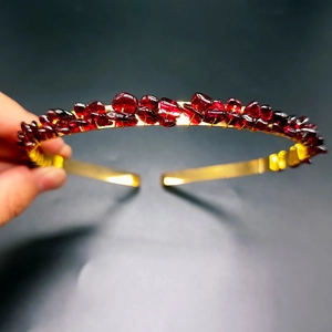 Detailed view of handmade gold crown headband with deep red crystal stones