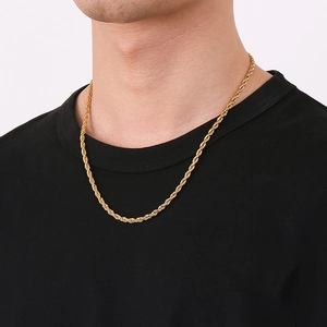 Close-up of a high-polish gold rope chain necklace worn by a model on a black background