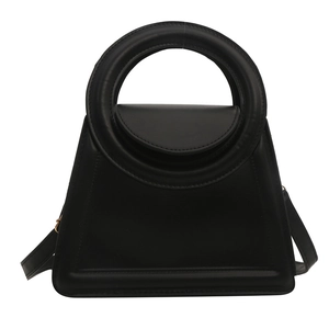 Minimalist black trapezoid handbag with unique circular handle and detachable strap
